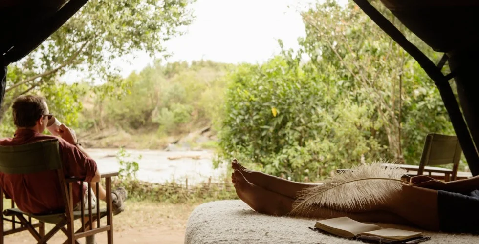 Guest enjoys a cuppa tea while marvelling at views of River Mara from his tent